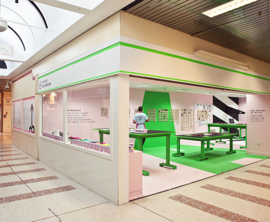 Vibrant space with a 1970s shopping centre. Lettering blocks line the walls with printing tables in the space.