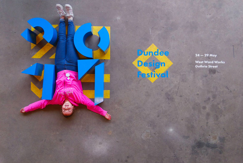 Woman lies upside down on floor surrounded by blocks of Dundee Design Festival 2017 logo