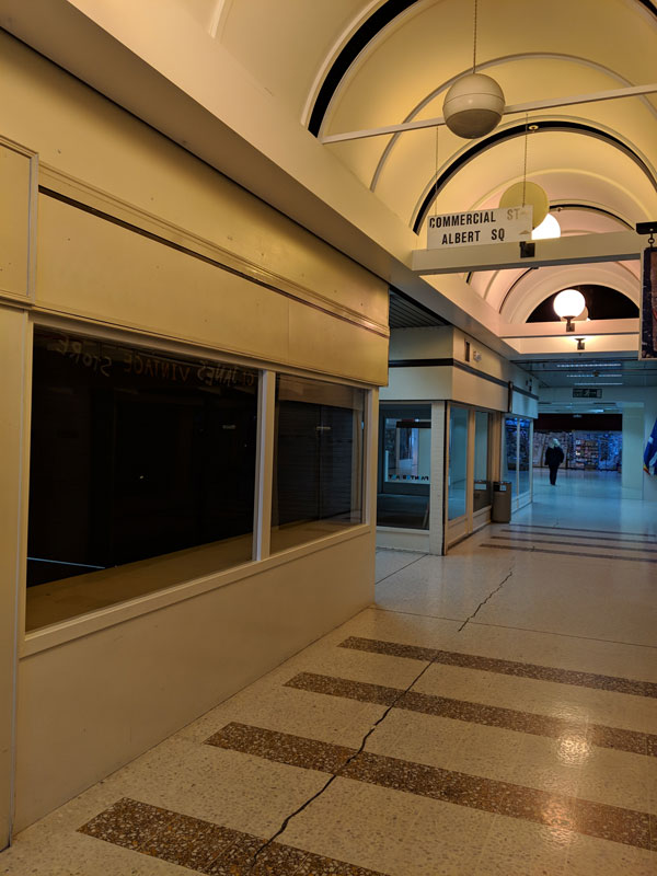 Interior corridor of shoping centre with empty windows.