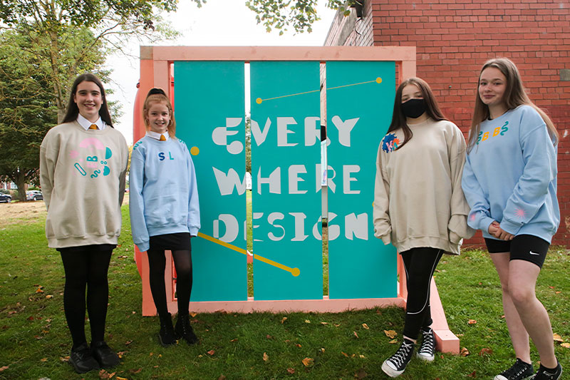 4 teenage girls stand infront of sign with the message Every Where Design